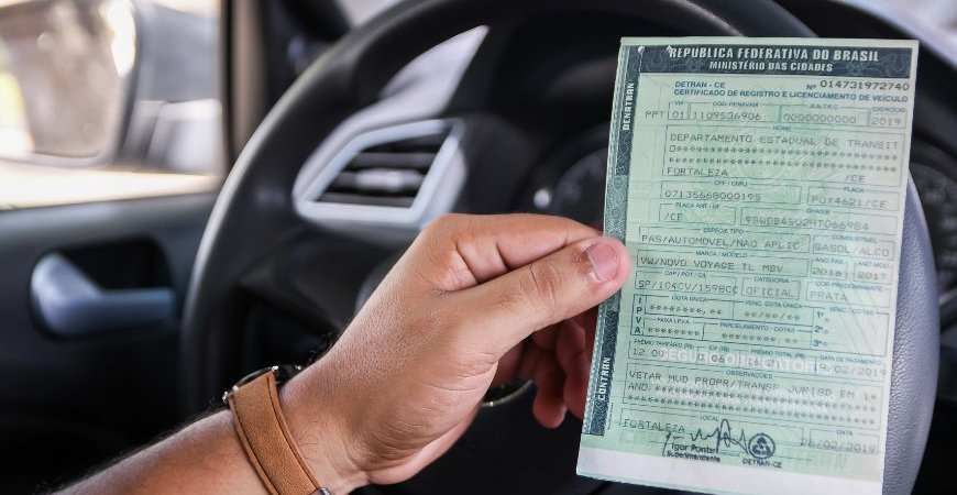 braço de uma pessoa segurando o documento do carro