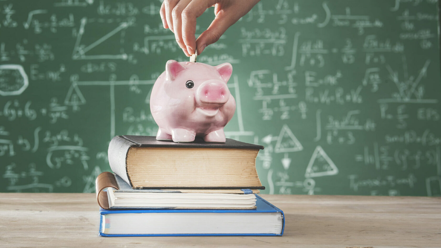 49 cofre de porquinho sobre livros, com fundo contendo quadro de giz de sala de aula